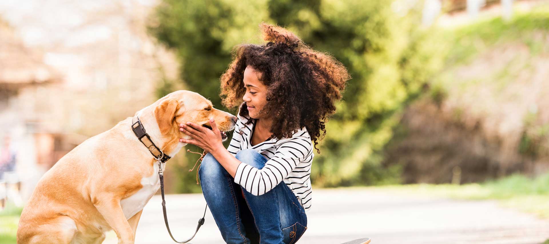 girl with curly hair caressing her pet dog on leash